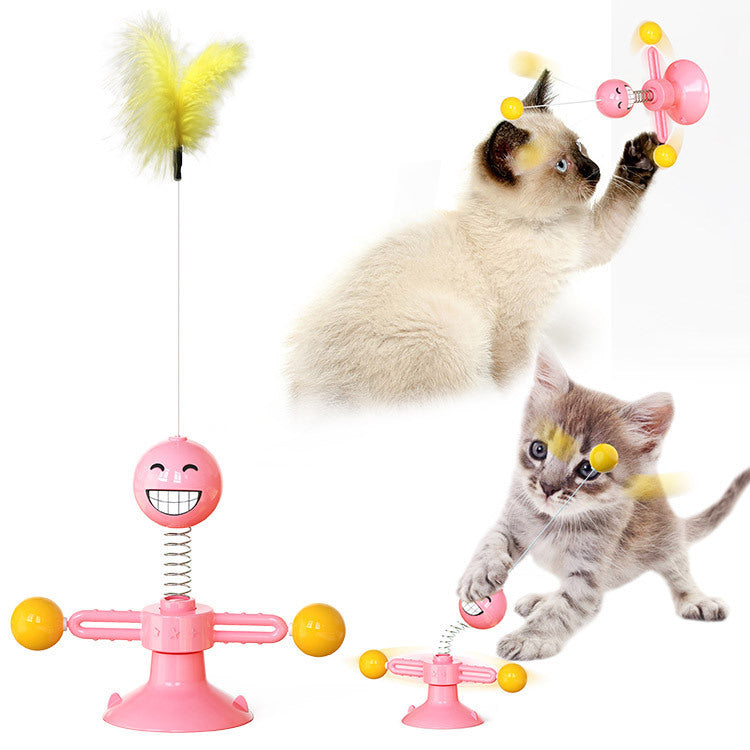 Cat playing with a pink toy featuring a spring and yellow feathers on a white background