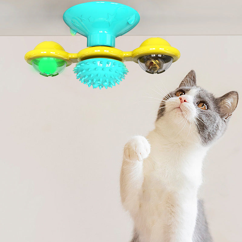 Cat playing with a colorful toy featuring green and yellow elements on a white background