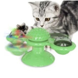 Cat playing with a green toy that has multiple levels and a small object on top.
