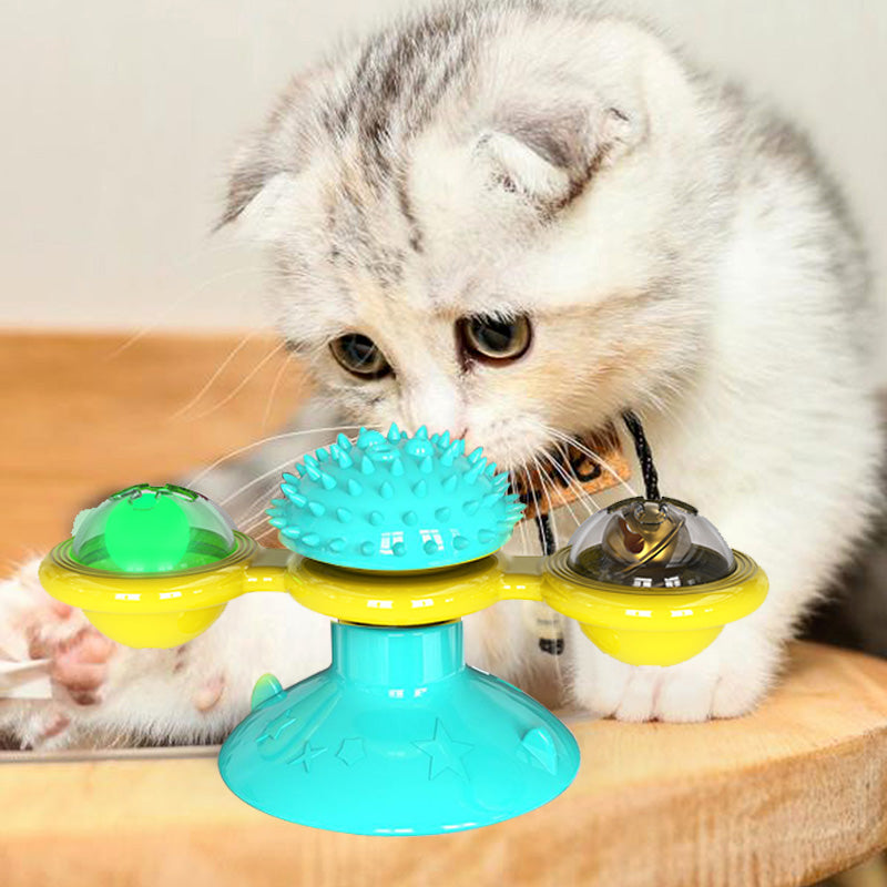 Cat playing with a colorful rotating pet toy on a wooden surface